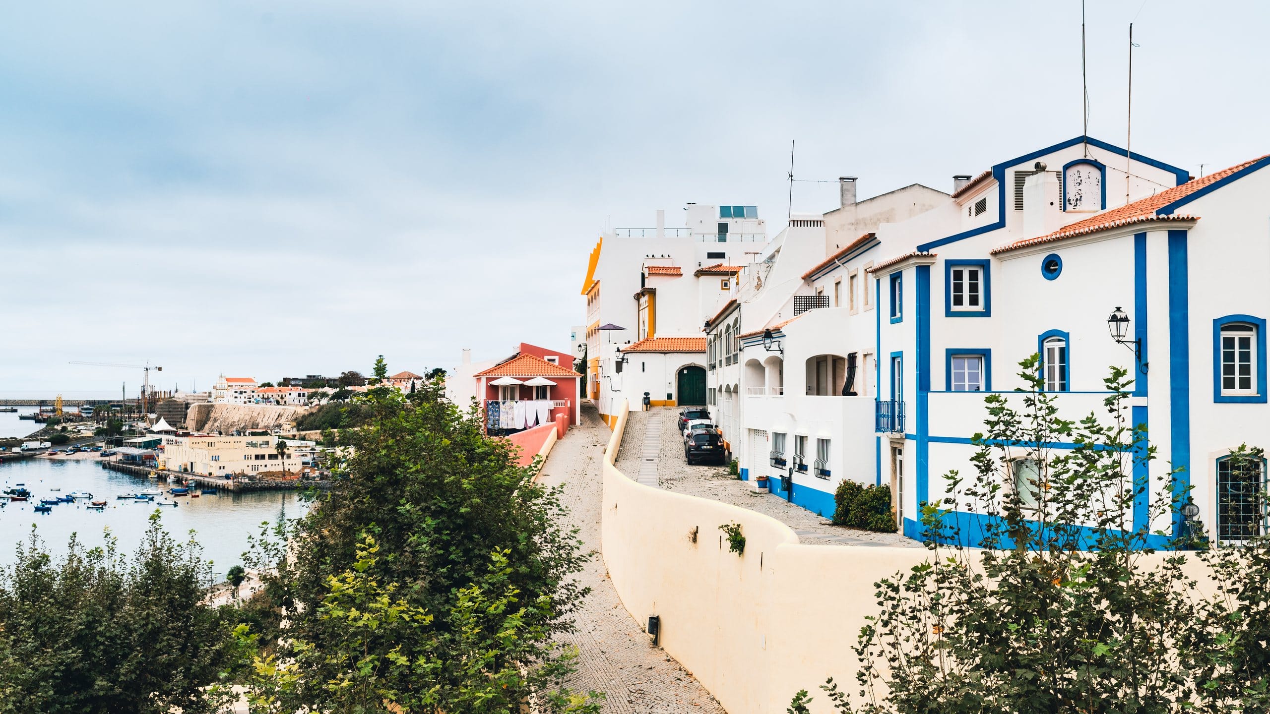 White houses with blue trim and terracotta roofs above a small harbour on the Portuguese coast